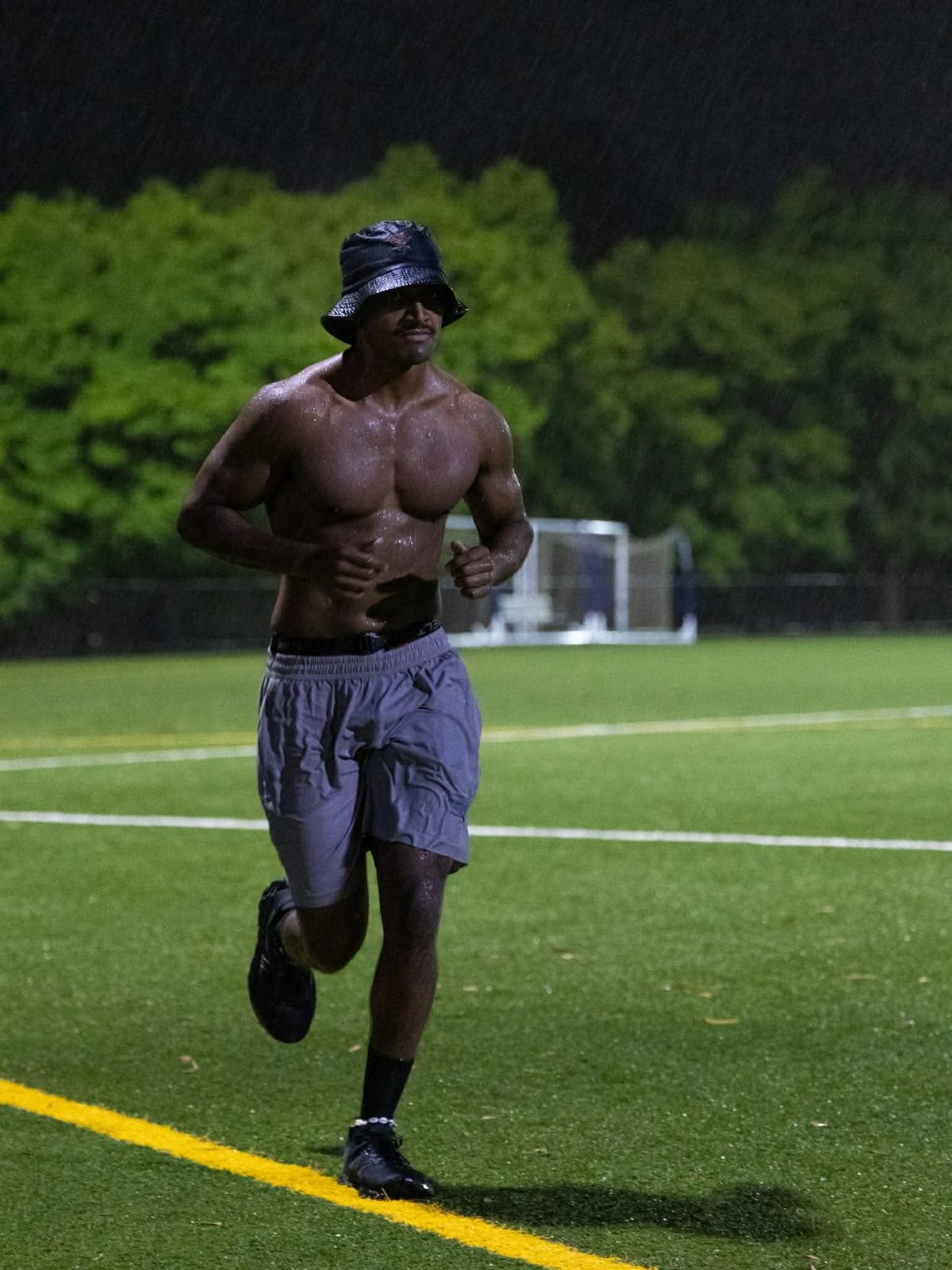Runners on the field at night in the rain